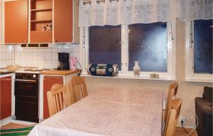エルムフルトにあるBeautiful Home In lmhult With Wifiのテーブルと窓のあるキッチン、テーブルと椅子が備わります。