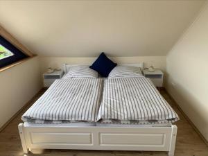 ein weißes Bett mit einem blauen Kissen in einem Zimmer in der Unterkunft Fewo-Hürtgenliebe in Hürtgenwald