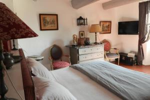 um quarto com uma cama, uma cómoda e uma televisão em La Nesquière Chambres d'Hôtes em Pernes-les-Fontaines