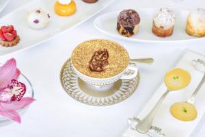 a cup of coffee on a table with pastries at Jumeirah Burj Al Arab Dubai in Dubai