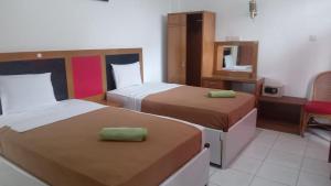 a hotel room with two beds and a mirror at Hotel Asia Bukittinggi in Bukittinggi