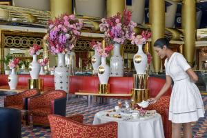a woman standing at a table in a restaurant with vases at Jumeirah Burj Al Arab Dubai in Dubai
