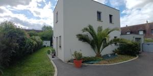 a white building with a palm tree next to it at grande maison entière de 120m2 in Épron