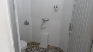 a white bathroom with a toilet and a shower at Hotel Asia Bukittinggi in Bukittinggi