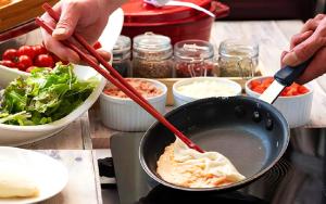 a person is cooking food in a wok at Hotel Monterey Kyoto in Kyoto