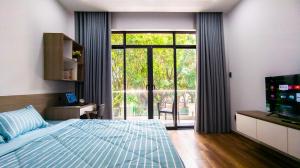 - une chambre avec un lit et une porte coulissante en verre dans l'établissement Marki Home, à Hô-Chi-Minh-Ville