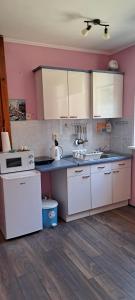 uma cozinha com electrodomésticos brancos e paredes cor-de-rosa em Apartmani Krcmarica 10 em Divčibare