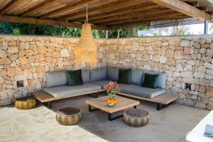 a patio with couches and tables and a stone wall at Villa Romero Renovated in Sant Rafael