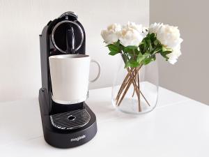 una macchinetta del caffè nera accanto a un vaso di fiori di Chelsea Flat 10 mins Harrods, Balcony, Gym, Air Conditioning a Londra