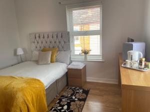 sypialnia z łóżkiem z żółtym kocem i oknem w obiekcie Protea Homestay w Manchesterze