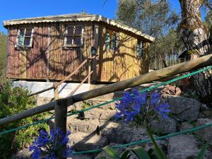 a wooden cabin with blue flowers in front of it at Quinta Laranja - Turismo Rural - in Alvorninha