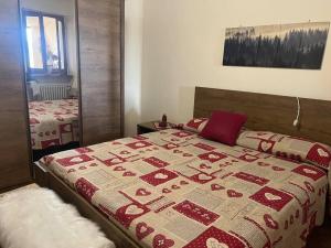 a bedroom with a bed with a red and white quilt at Appartamento “Sut l’Ala” in Netro