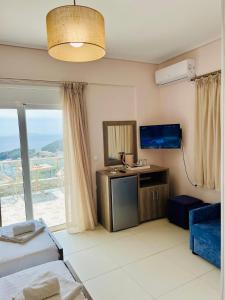 a hotel room with a bed and a tv and a window at Mistral Inn in Himare