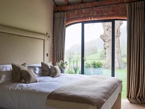 a bedroom with a large bed and a large window at The Carthouse in Ledbury