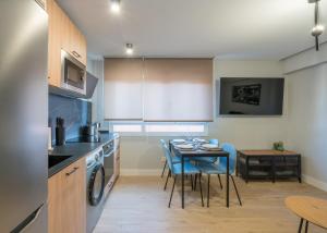 a kitchen with a table and blue chairs in a room at Villa Hita apartment by People Rentals in Bilbao