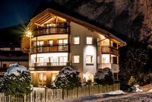 a large building with lights on in the snow at Apartments Aghel ***S in Selva di Val Gardena