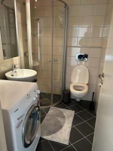 a bathroom with a washing machine and a toilet at Marken Apartments in Bergen