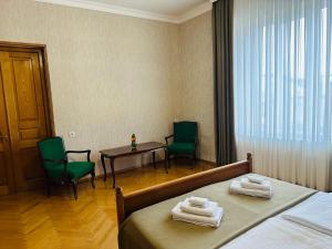 een hotelkamer met 2 bedden en een tafel en stoelen bij Guest House Kartuli Suli in Telavi