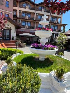 une grande fontaine blanche avec des fleurs devant un bâtiment dans l'établissement Ferdinand, à Moukatcheve