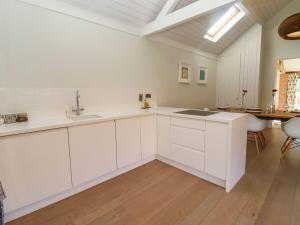 cocina con armarios blancos y suelo de madera en The Piggery, en Ledbury