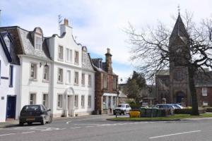 a street with a white building and cars parked on the street at East Linton flat, sleeps 2 in East Linton
