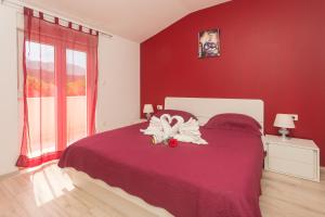 ein Schlafzimmer mit einem Bett mit einer roten Wand in der Unterkunft Villa Tomic in Trnbusi