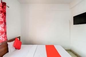 Schlafzimmer mit einem Bett mit roten Kissen und einem TV in der Unterkunft Flagship Hotel Creation Premium in Sānkchi