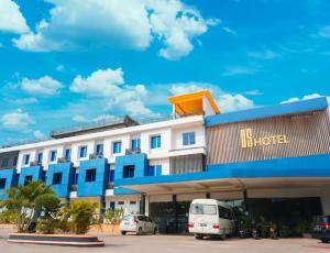ein blau-weißes Hotel mit auf einem Parkplatz geparkten Autos in der Unterkunft OS Hotel Tanjung Uncang in Sagulung