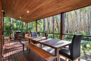 a screened in porch with a wooden table and chairs at Buddha's Bungalow in Byron Bay