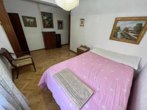 a bedroom with a pink bed and a chair at Piso amplio y acogedor in Madrid
