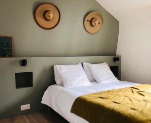 ein Schlafzimmer mit einem Bett mit zwei Hüten an der Wand in der Unterkunft « La Divine » Maison de pêcheur bord de mer in Dives-sur-Mer