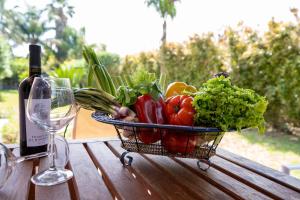 a basket of vegetables on a table next to a bottle of wine at Villa Green Place in Mascali +20 photos