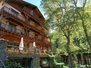 ein großes Holzgebäude mit Balkonen und einem Baum in der Unterkunft Hotel Estanys Blaus in Tavascan