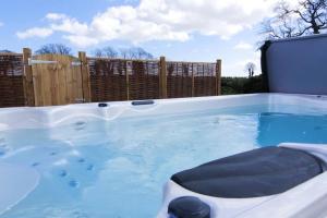 a hot tub in a backyard with a wooden fence at Covehithe House-Coastal luxury- sleeps 12-with huge swimspa! in Wrentham