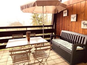 a table and a bench and an umbrella on a porch at Les Frênes in Leysin