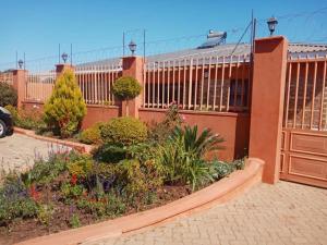 a fence with a garden in front of a building at Beautiful guesthouse with pool and solar - 2057 in Victoria Falls