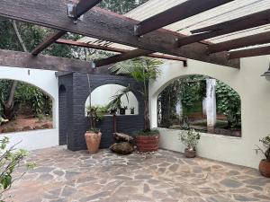 an outdoor patio with arches and potted plants at Cozy 3 Bedroom House with unique bathrooms - 2084 in Bulawayo