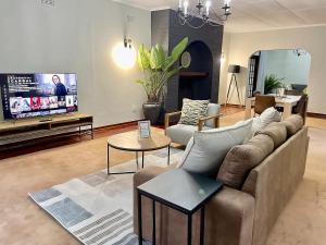 Il comprend un salon doté d'un canapé et d'une télévision à écran plat. dans l'établissement Cozy 3 Bedroom House with unique bathrooms - 2084, à Bulawayo