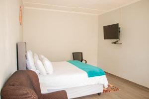 a bedroom with a bed and a tv on the wall at Standard room in Morningside guesthouse - 2090 in Bulawayo