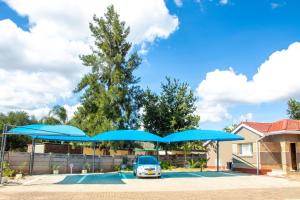 a car parked in a parking lot with blue umbrellas at Standard room in Morningside guesthouse - 2090 in Bulawayo