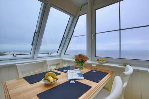 una sala da pranzo con tavolo e alcune finestre di Villa Marina - Gigantischer Meerblick a Wangerooge