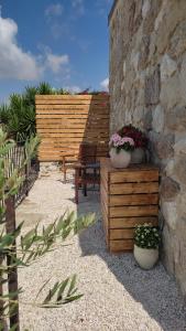 un patio avec un banc en bois et deux plantes en pot dans l'établissement Borgo delle Pietre, à Porto Empedocle