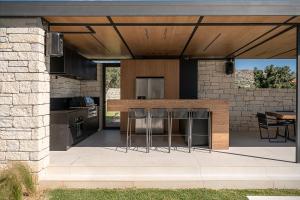 een buitenkeuken met een bar met krukken bij Searenity Villa in Chania +64 foto's