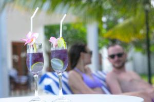 NN Beach Resort & SPA في نيلافيلي: كأسين مع مشروبات على طاولة مع زوجين