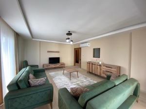 a living room with two green couches and a television at YALINCAK EŞYALI KİRALIK DAİRE in Uğurlu