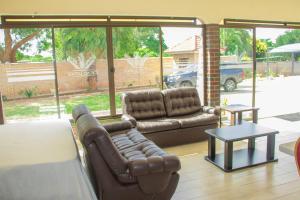 uma sala de estar com dois sofás de couro e uma mesa em Neat one bedroom in Morningside guesthouse - 2091 em Bulawayo