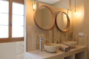 two sinks in a bathroom with mirrors on the wall at Mas neuf de Romanin : Mas Provençal Familial in Saint-Rémy-de-Provence