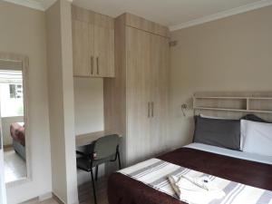 Habitación pequeña con cama y escritorio. en 2 bedroomed apartment with en-suite and kitchenette - 2071 en Harare