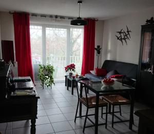 a living room with a table and red curtains at Res au calme et arboree in Dax