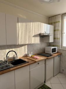 cocina con armarios blancos, fregadero y microondas en Apartament Bazyliańska - 100m do Metra "Bródno", 20 minut do centrum Warszawy en Varsovia